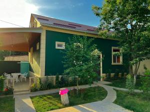 a green and yellow house with a table and chairs at Qafqaz Mini Villa in Gabala