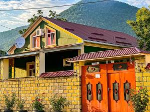 una casa con una puerta naranja delante de ella en Qafqaz Mini Villa, en Gabala