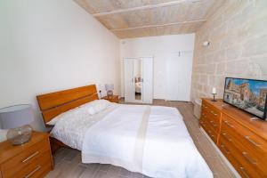 a bedroom with a bed and a flat screen tv at Central Valletta Townhouse-Hosted by Sweetstay in Valletta