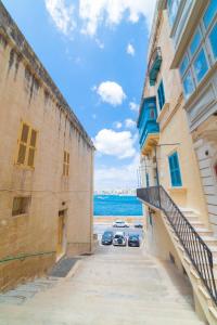 ein Gebäude mit zwei Autos neben dem Meer in der Unterkunft Central Valletta Townhouse-Hosted by Sweetstay in Valletta