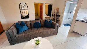 a living room with a brown couch with blue pillows at Zinathi Lodge in Polokwane