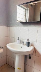a bathroom with a white sink and a mirror at Zinathi Lodge in Polokwane +21 photos