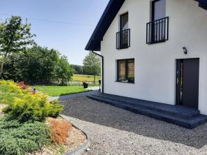 a house with a black door and a gravel driveway at Agroturystyka Zdolina in Krajno Pierwsze