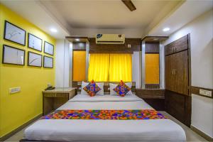 a bedroom with a large bed and a yellow wall at FabHotel Adri Hotel's in Dum Dum