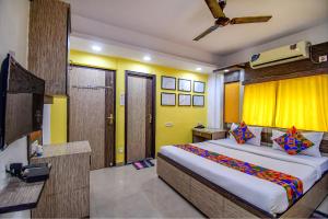 1 dormitorio con 1 cama grande y pared amarilla en FabHotel Adri Hotel's en Dam Dam