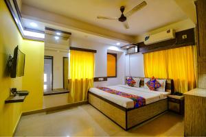 a bedroom with a large bed with yellow curtains at FabHotel Adri Hotel's in Dum Dum