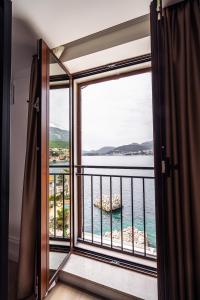 a room with a view of the ocean from a balcony at Blanche Cliff Apartments in Sveti Stefan