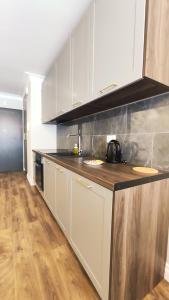 uma cozinha com armários brancos e piso em madeira em Ariańska 8A by Homeprime em Cracóvia