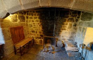 a stone fireplace with a bench in front of it at Le petit château du Villard in Le Malzieu Forain