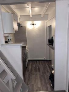 a kitchen with white cabinets and a hallway with a door at Au pied du Baou in Saint-Chamas