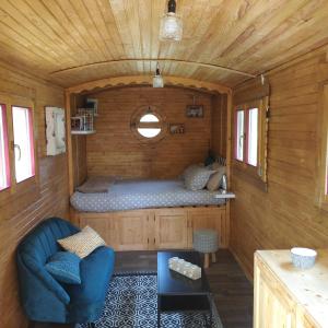 um pequeno quarto com uma cama num chalé de madeira em Les roulottes du Moulin de Palet 