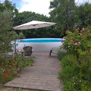 un patio con sombrilla, sillas y flores en Les roulottes du Moulin de Palet 