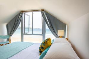 a bedroom with a bed and a large window at Tolcarne Beach Apartments in Newquay