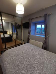 1 dormitorio con cama y espejo grande en Cosy 1 bedroom cottage, Ideal quiet getaway. en Creeslough