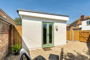 un pequeño cobertizo blanco con puertas verdes en un patio en the Beach House, en Kent