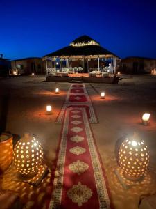 a table with candles and a gazebo at night at Aladdin Desert Camp - Mhamid Erg Chigaga Escape in El Gouera +34 photos