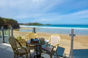 a table and chairs on a patio with a beach at Tolcarne Beach Apartments in Newquay