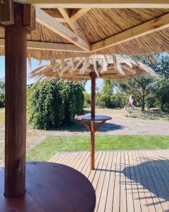 een picknicktafel onder een houten parasol op een patio bij Ostrovia - pokoje nad morzem in Ostrowo