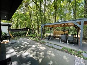 een patio met een tafel en stoelen onder een paviljoen bij Cosy Tiny Lodges - vakantiepark Kempenbos in Diessen