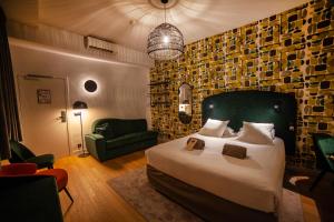 een slaapkamer met een groot bed en een groene stoel bij Hotel Kanaï in Lille