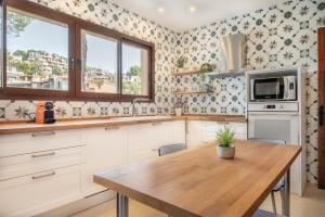 a kitchen with white cabinets and a wooden table at Villa Rivo - Costa de la Calma in Costa de la Calma