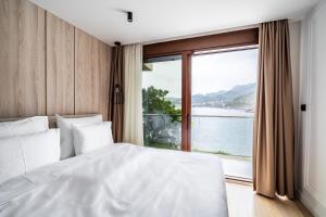 a bedroom with a white bed and a large window at Blanche Cliff Apartments in Sveti Stefan