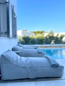 a couple of couches sitting next to a pool at SUNSENSES luxury VILLAS Paros in Piso Livadi +286 photos