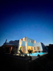 a large white house with a swimming pool at night at SUNSENSES luxury VILLAS Paros in Piso Livadi