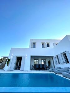 a white house with a swimming pool in front of it at sun senses luxury Vilas Dione in Piso Livadi