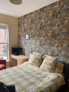a bedroom with a bed and a wall with a wallpaper at Lwr Ormeau Guest House in Belfast