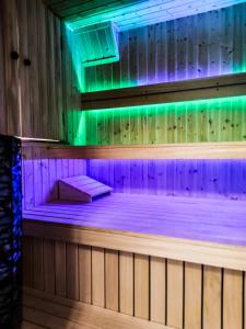 una sauna con luces moradas y verdes en Szostak Apartament, en Bańska Niżna
