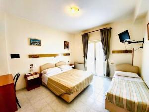 una camera d'albergo con due letti e una televisione di Albergo delle Rose a Bagnara Calabra