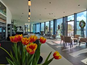 eine Lobby mit orangefarbenen Tulpen, Tischen und Stühlen in der Unterkunft Domein Polderwind in Zuienkerke
