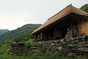 a house with a stone wall next to a building at Chiiori in Miyoshi