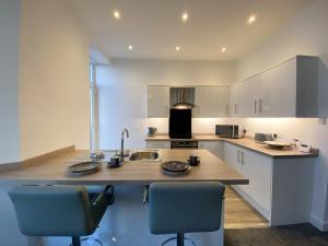 una cocina con fregadero y 2 sillas. en Eden Escapes Serviced Apartments, en Morecambe