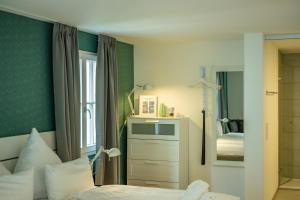 een kleine slaapkamer met een bed en een spiegel bij Gästehaus am Schlossplatz, Z. 2 in Meersburg +19 foto's