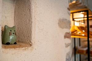 a small green cat figurine sitting on a wall at Passage en Paradis in Arbois