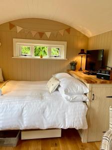 a bedroom with a white bed and a television at Sheelin Shepherds Hut 2 with Hot Tub in Mountnugent