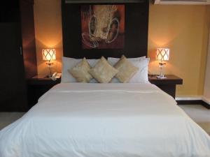 マニラにあるオイスター プラザ ホテルのベッドルーム(白い大型ベッド、ランプ2つ付)