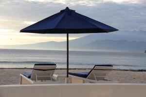 
a table with chairs and umbrellas on a beach at Seri Resort Gili Meno in Gili Meno
