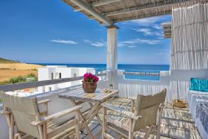 een tafel en stoelen op een balkon met uitzicht op de oceaan bij Ιάνθη Ianthi Boutique Guesthouses Skyros in Skiros