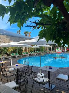 a swimming pool with tables and chairs in front of a building at Park Hotel Cellini in Lido di Jesolo