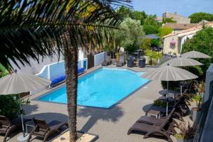 a large swimming pool with chairs and umbrellas at Hôtel Le Peu Breton in Sainte-Marie-de-Ré