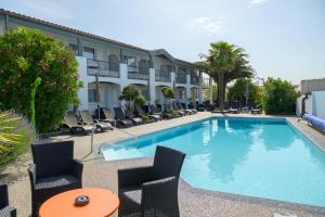 une piscine avec des chaises et un hôtel dans l'établissement Hôtel Le Peu Breton, à Sainte-Marie de Ré