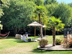 een tuin met stoelen en een parasol en palmbomen bij Hotel Restaurant Du Parc Saumur Logis Elégance in Saumur