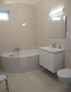 a bathroom with a tub and a sink and a toilet at Tandem apartman in Kápolnásnyék