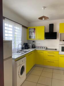 a kitchen with yellow cabinets and a washing machine at Love Guadeloupe in Sainte-Anne