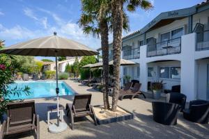 a hotel with chairs and an umbrella next to a swimming pool at Hôtel Le Peu Breton in Sainte-Marie-de-Ré