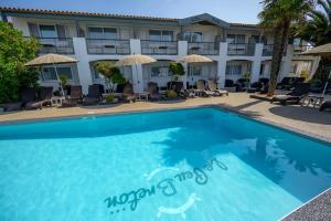 a swimming pool in front of a hotel at Hôtel Le Peu Breton in Sainte-Marie-de-Ré