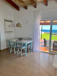 una sala da pranzo con tavolo, sedie e vista sull'oceano di Villa Calma a Cala'n Bosch